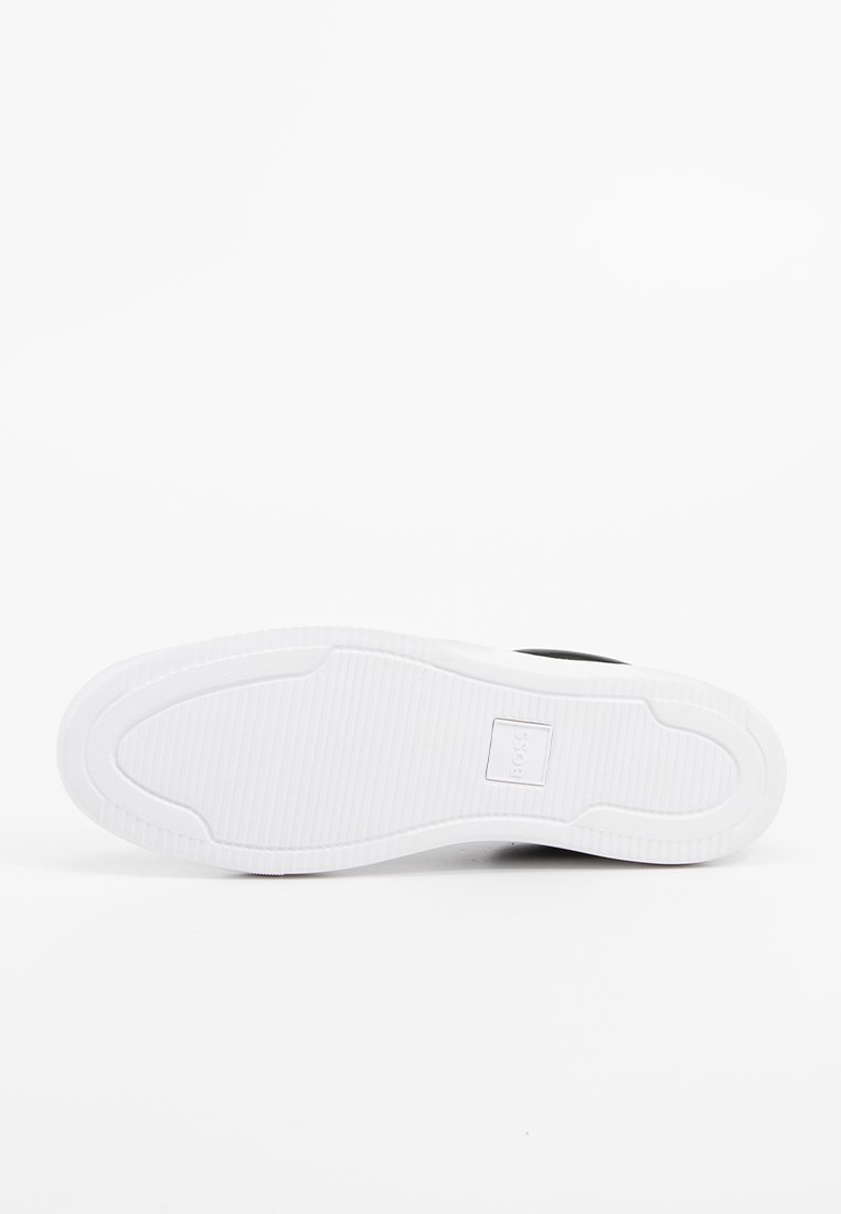 Suola nera di una scarpa da ginnastica con una suola in gomma bianca texturizzata, caratterizzata da un dettaglio logo rettangolare e un design con bordi lisci.