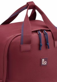 Borsa da viaggio bordeaux con manici blu navy, caratterizzata da un'esterno a superficie liscia, chiusura con doppia cerniera e etichetta con logo sul fronte.
