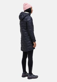 Dark blue puffer coat with wave pattern, attached hood, knee-length. Worn over black leggings and gray running shoes, with a pink beanie.