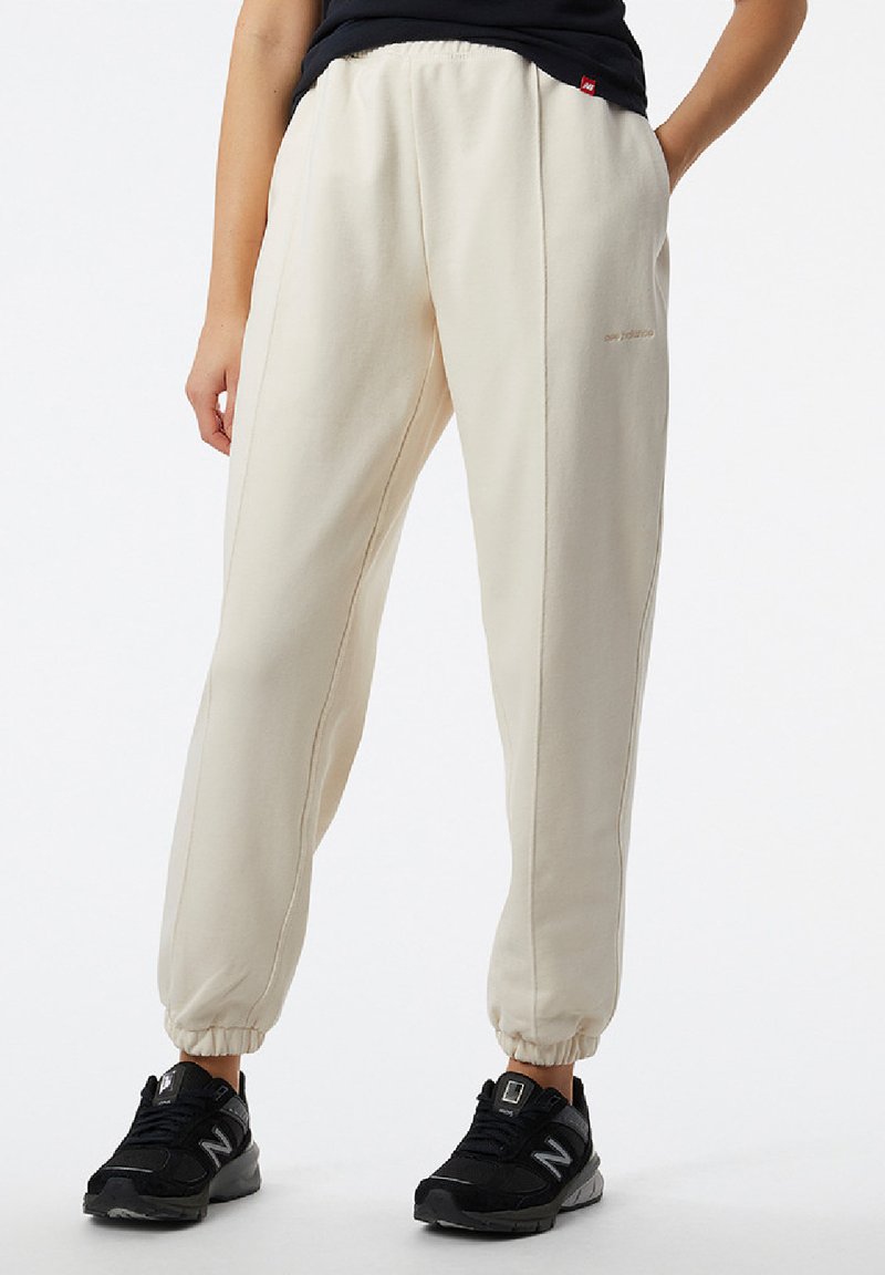 Cremfarbene Joggingpants mit einem elastischen Bund und Bündchen, ausgestattet mit dezenten Seitennähten und gestickter Markenwerbung am Bein.