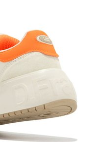 Sneaker con tomaia in suede bianco con accento arancione, patch logo rotondo e suola chunky color crema con dettagli testurizzati.