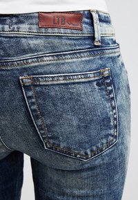 Jeans en denim bleu délavé avec une étiquette en cuir LTB à la taille. Présentent des poches arrière cousues et une finition texturée.