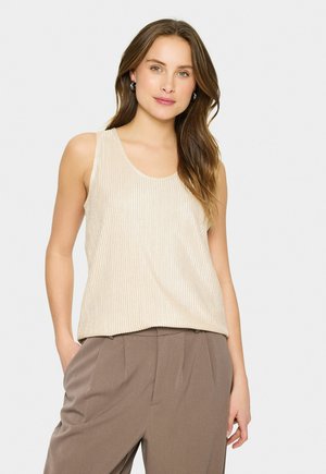 Beige geripptes Tanktop mit einem Rundhalsausschnitt, das einen entspannten Schnitt und eine glatte Textur bietet. Das Modell kombiniert es mit beigen Hosen.