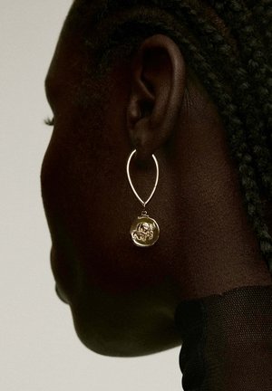 Pendiente de aro dorado con un colgante circular texturizado y un diseño detallado, suspendido de un cierre delgado y redondeado.