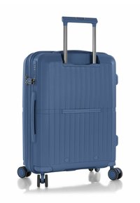 Valigia rigida blu con superficie texture, strisce verticali, manico estraibile e quattro ruote girevoli per la mobilità.