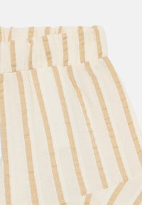 Lätt tyg med vertikala kräm- och beighe-stripes, med en samlad elastisk midja och mjuk, texturerad yta.