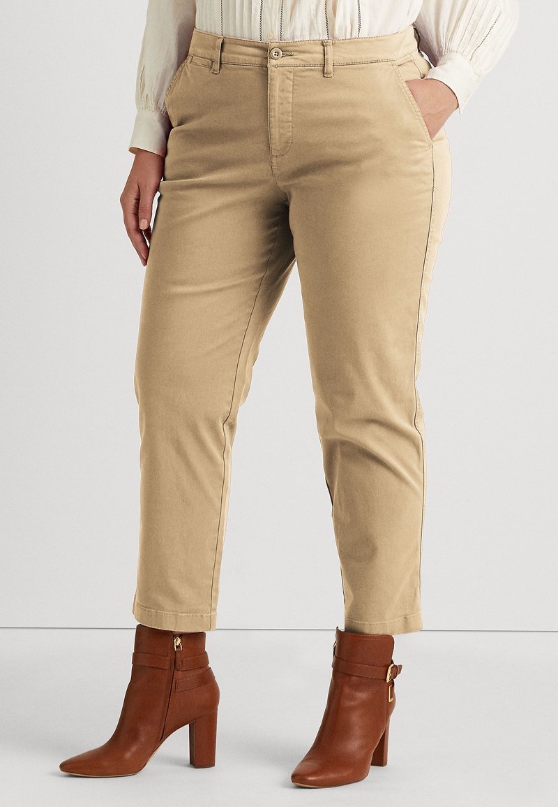 Beige cotton blend trousers with tailored fit, front pockets, and contrasting stitching, paired with brown ankle boots with a buckle accent.