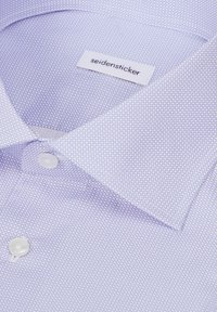 Chemise habillée violet clair avec un petit motif circulaire, des boutons blancs et une étiquette avec le nom de la marque "seidensticker" à l'intérieur du col.
