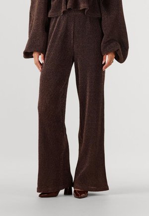 Brown ribbed knit wide-leg pants feature a textured finish and a relaxed fit, paired with glossy brown heeled shoes.