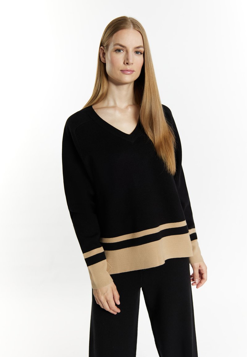 Maglione nero a maglia con scollo a V, caratterizzato da un orlo e dei polsini a strisce beige. Il tessuto sembra morbido con una consistenza liscia.