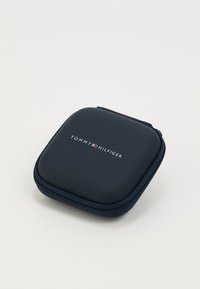 Tommy Hilfiger marinblå hård väska med en jämn yta, dragkedjestängning och logga som är tydligt placerad på framsidan. Kompakt kvadratisk form.
