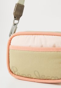 Beige og pastel pink crossover taske med quiltet tekstur, gummilogo detaljer og en holdbar rem med metalhardware.