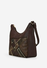 Bolso de hombro de cuero marrón oscuro con tachuelas doradas y un patchwork floral grabado, cuenta con un cierre superior y una correa ajustable.