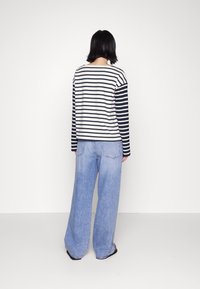 Lange mouw gestreepte top in wit en marineblauw, gecombineerd met wijde lichtblauwe jeans met contrasterende stiksels. Eenvoudige, ontspannen silhouet.