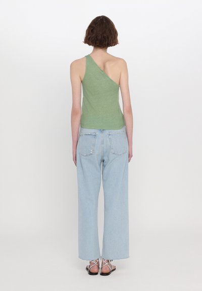 Grön enaxlad topp gjord av ett texturerat tyg, parat med högmidjade ljusblå raka jeans och sandaler med remmar.