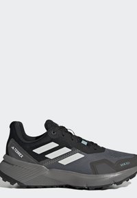 Čierno-sivá trailová bežecká topánka Adidas Terrex s bielymi pruhmi, čiernymi šnúrkami a štítkom "RAIN RDY" na strane prsta.