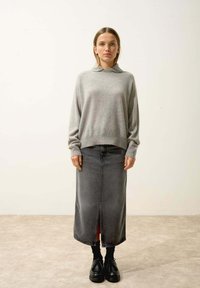 Szary, dzianinowy sweter z kołnierzykiem, zestawiony z długą, rozciętą czarną spódnicą dżinsową i czarnymi sznurowanymi butami. Płaska, gładka faktura, casualowy design.