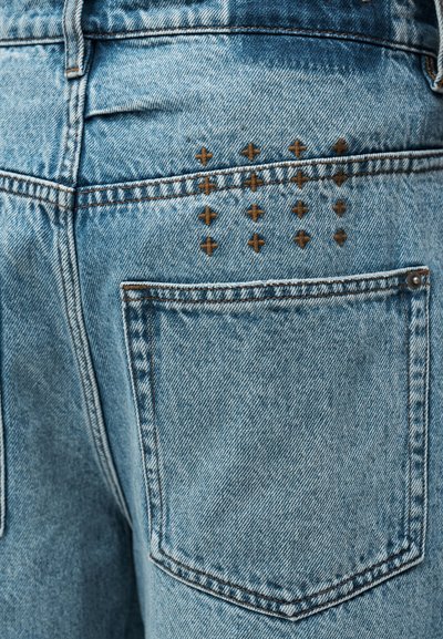 Ανοιχτό μπλε τζιν παντελόνι με μια πίσω τσέπη που διαθέτει διακοσμητικό ράψιμο σε σχήμα σταυρού. Το υλικό έχει υφή με ορατή ξεθώριασμα.