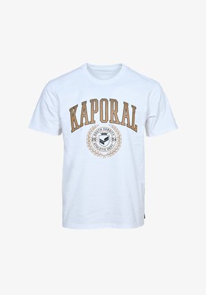 Camiseta de algodón blanca con un gran estampado marrón de "KAPORAL" y un logotipo circular con diseño de laurel en el centro, de mangas cortas y cuello redondo.