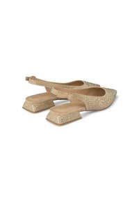 Chaussures slingback beiges avec un bout pointu, dessus texturé orné de clous métalliques, et un talon chunky à motif géométrique.