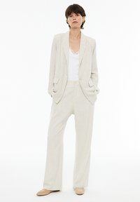 Light beige linen blazer paired with matching wide-leg pants. The outfit features a white lace-trimmed camisole underneath.