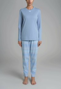 Maglietta da pigiama azzurro chiaro a maniche lunghe con scollatura decorativa, abbinata a pantaloni blu con motivo geometrico. Tessuto in cotone morbido.