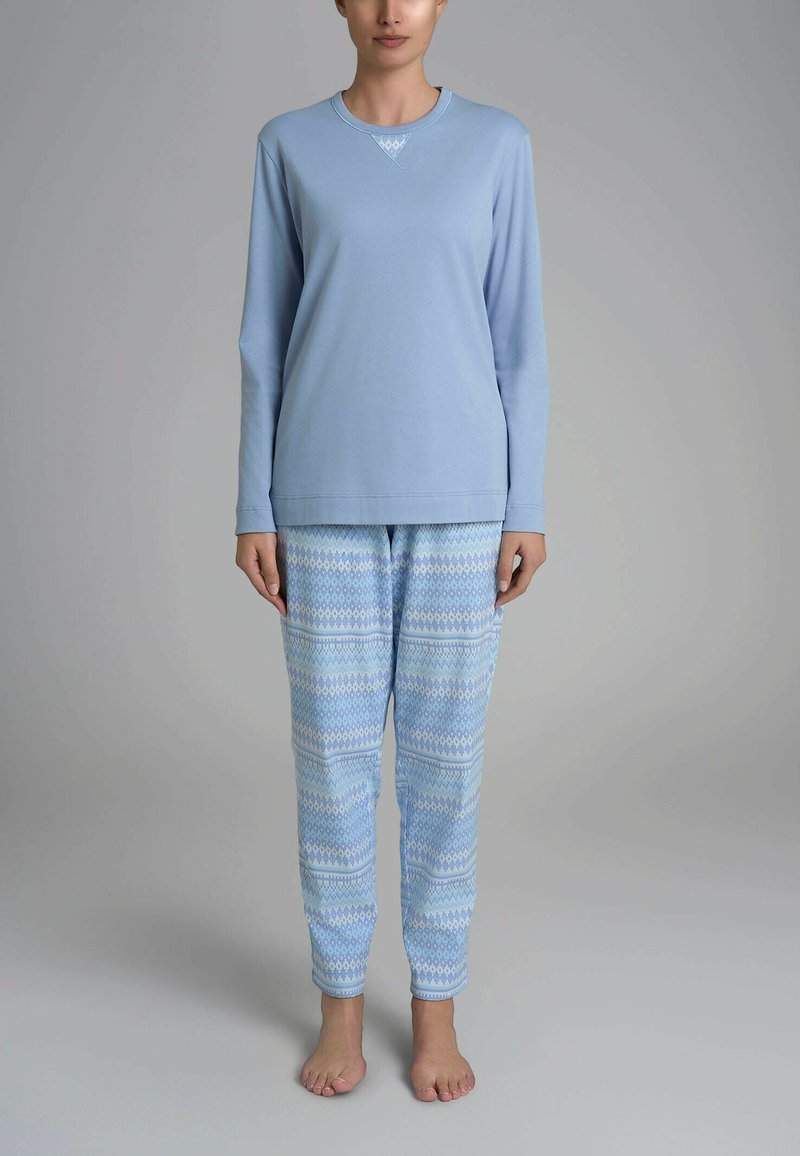 Maglietta da pigiama azzurro chiaro a maniche lunghe con scollatura decorativa, abbinata a pantaloni blu con motivo geometrico. Tessuto in cotone morbido.