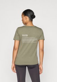 Camiseta de manga corta color verde oliva con texto en la parte posterior. Material de algodón. Corte recto. Diseñada para la comodidad, adecuada para actividades al aire libre.