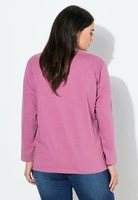 Camicia a maniche lunghe di colore rosa chiaro, realizzata in morbido cotone. Presenta un collo rotondo e un design semplice senza modelli o accenti visibili.