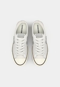 Grey suede sneakers with a rubber toe cap, flat laces, and perforated accents. Features a monochromatic star logo on the side.