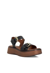 Zwarte leren platform sandalen met verstelbare banden en gouden gespen. De houten zool voegt hoogte en contrast toe aan het ontwerp.