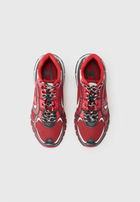 Red athletic shoes with mesh fabric upper, black accents, reflective details, and textured soles. Features black and silver laces.