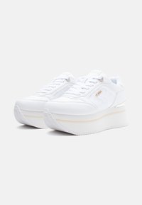 Sneaker bianche con piattaforma, pannelli laterali trapuntati, lacci e un piccolo dettaglio in metallo sul lato esterno di ogni scarpa.