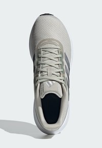 Svetlošedá športová obuv s priedušným zvrškom, zelenými akcentmi a tmavosivým brandingom. Obsahuje ploché šnúrky a zaoblenú, polstrovanú podrážku.