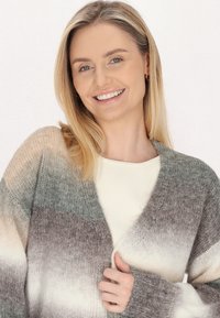 Cardigan lavorato a maglia in tonalità gradienti di grigio, crema e marrone; apertura frontale, maniche lunghe, texture morbida e polsini a coste.