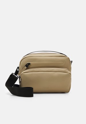 Borsa a tracolla color tan realizzata in materiale liscio, con due scompartimenti con zip, una tracolla nera regolabile e dettagli di design minimalisti.
