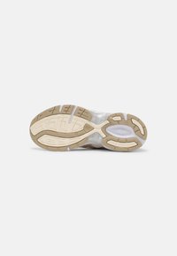 Sports shoe sole with a translucent rubber section, featuring a multi-patterned grip design in tan and off-white colors.