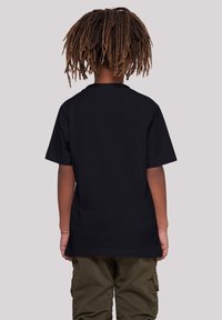 Black short-sleeve t-shirt with a crew neckline, featuring a smooth texture and slightly relaxed fit, worn with olive green pants.