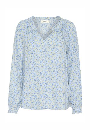 Blusa azzurro chiaro a maniche lunghe con scollo a V, motivo floreale giallo e blu, e dettagli arricciati sul collo e sui polsini.