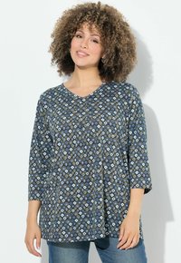 Maglietta stampata con scollatura a V, maniche a tre quarti e un motivo geometrico nei toni blu, bianco e scuri. Tessuto morbido con una vestibilità comoda.