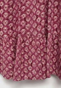 Ruffled cotton skirt in a muted burgundy color, featuring a cream floral pattern with diamond shapes and textured fabric.