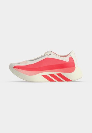 Chaussure de sport de couleur claire avec motif en vague rouge vif et trois bandes rouges sur une semelle épaisse, vue de profil sur fond blanc.