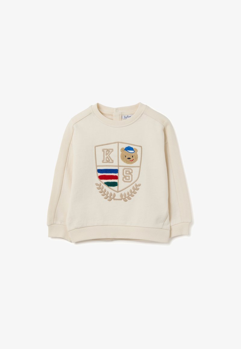 Sudadera color crema con puños y dobladillo acanalados, que presenta un parche bordado en forma de escudo con "K", "S" y un diseño de oso de peluche.