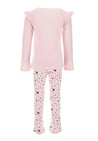 Top de manga larga rosa claro con hombros con volantes, combinado con pantalones rosas que presentan un patrón de lunares y pequeños acentos en negro.