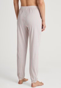 Gestreepte loungebroek van lichte stof, met verticale pastelstrepen in roze en groen, elastische tailleband en taps toelopende boorden bij de enkels.