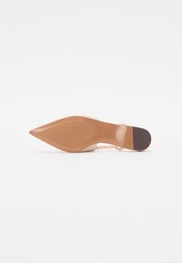 Nude høyhælte sko med spiss tå, transparente reimer og en teksturert brun såle. Har en slank silhuett og minimalt med detaljer.