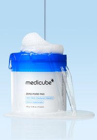 Medicube Zero Pore Pad-behållaren har en genomskinlig kropp med ett blått lock, som visar runda bomullspads med texturerad yta för hudvård.