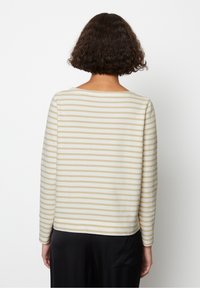 Gestreepte longsleeve top in crème en beige met een bootnek en een ontspannen pasvorm. Zachte textuur, afgewerkte zoom en zijsplitten.