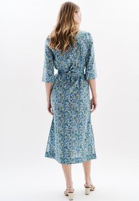 Robe à imprimé floral bleu, dotée de manches trois-quarts, d'une taille à nouer et d'une longueur midi, fabriquée dans un tissu léger.