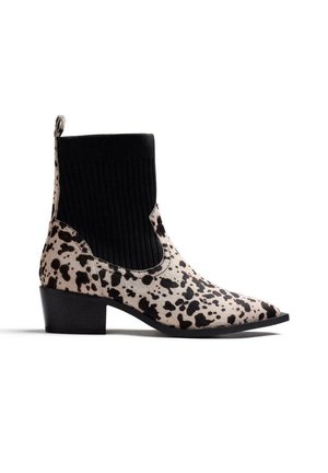Stivaletto alla caviglia nero di media altezza con tacco, punta appuntita e tomaia bianca con macchie nere irregolari, collo elastico nero a maglia e linguetta sul tallone.